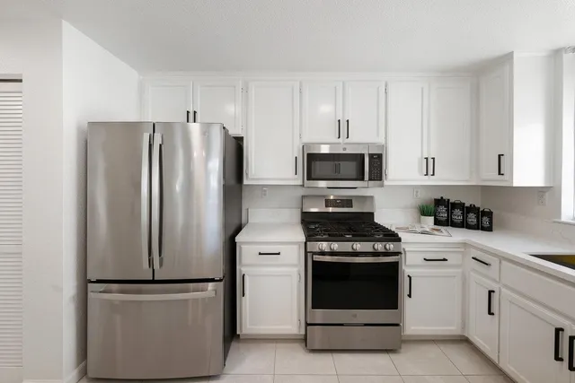 a kitchen with cabinets appliances a sink and a window