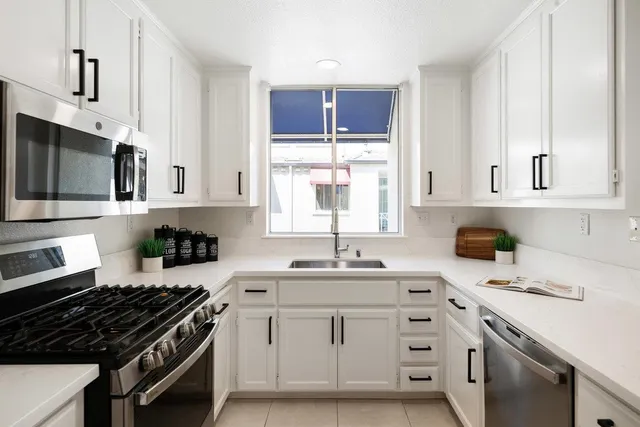 a kitchen with white cabinets and chandelier