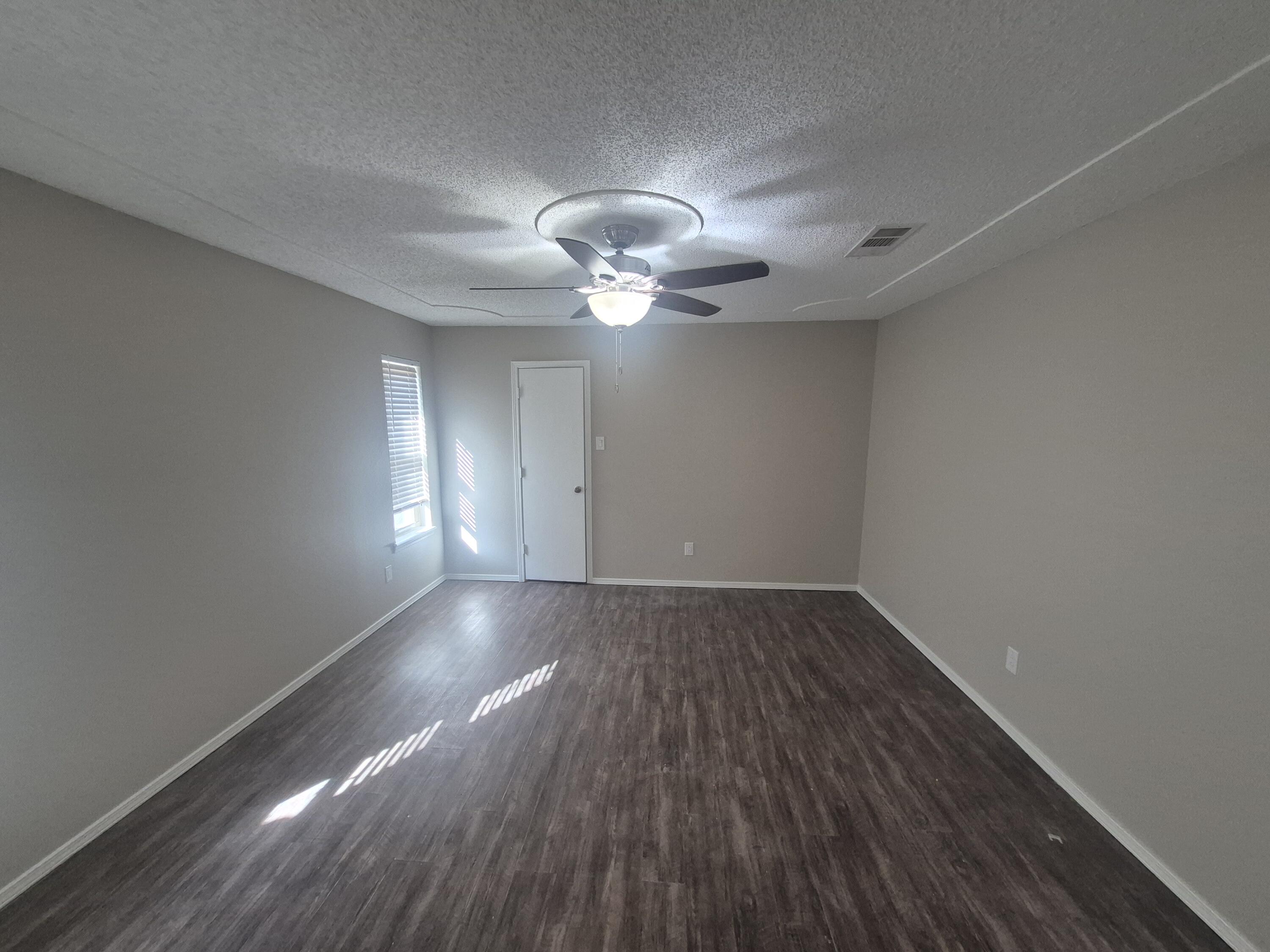 3211 94th Street Lubbock, TX 79423 - Photo 11 of 24 a view of an empty room with wooden floor and a window
