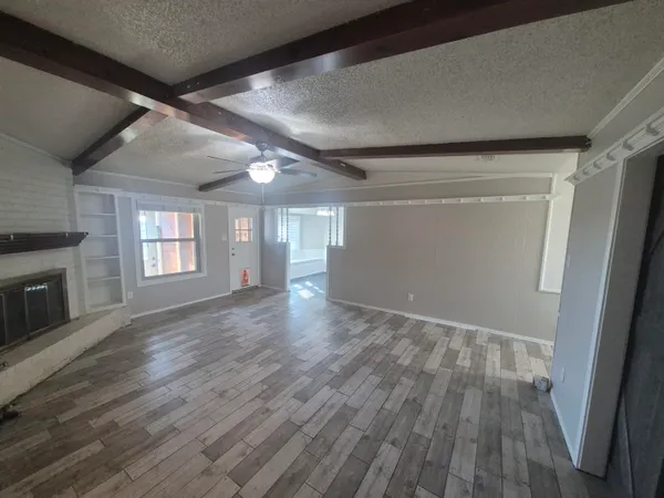 a view of empty room with wooden floor and fireplace