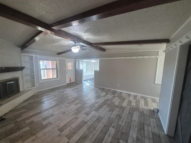 a view of empty room with wooden floor and fireplace