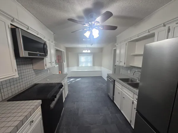 a kitchen with stainless steel appliances granite countertop a sink a stove top oven a chimney with wooden floor and cabinets