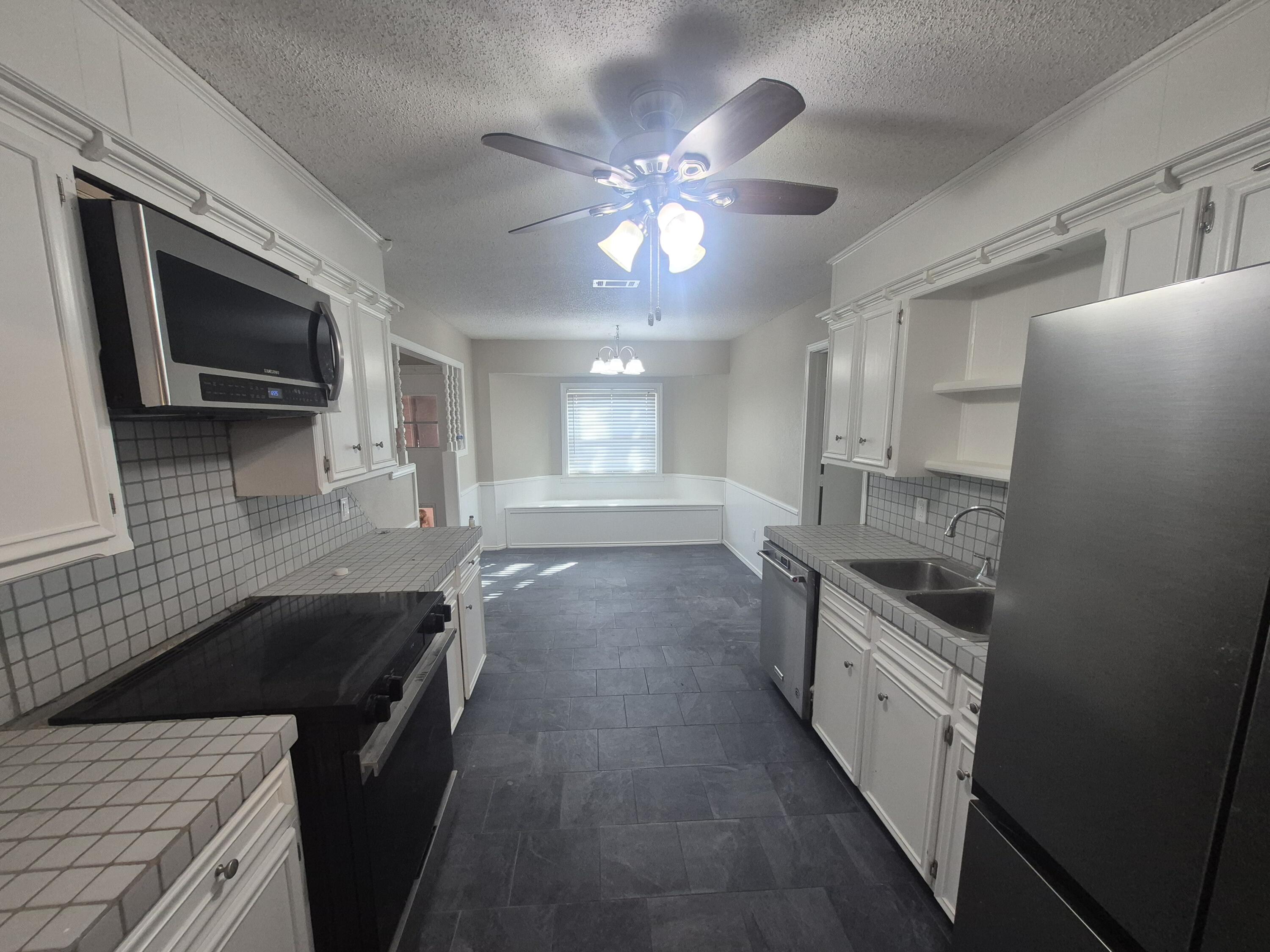 3211 94th Street Lubbock, TX 79423 - Photo 8 of 24 a kitchen with stainless steel appliances granite countertop a sink a stove top oven a chimney with wooden floor and cabinets