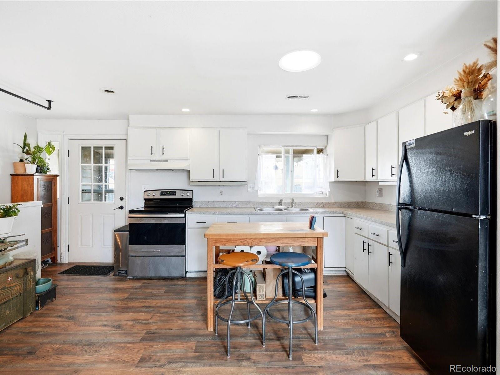 360 South 7th Avenue Brighton, CO 80601 - Photo 12 of 43 a kitchen with stainless steel appliances granite countertop a refrigerator a stove a sink a dining table and chairs with wooden floor