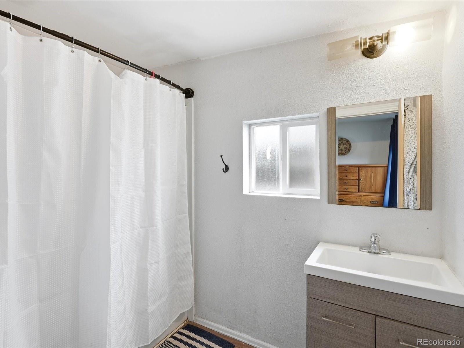 360 South 7th Avenue Brighton, CO 80601 - Photo 28 of 43 a bathroom with a sink a mirror and a shower curtain