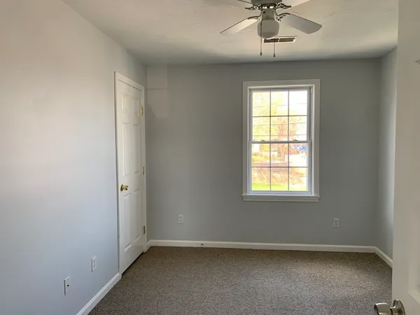 an empty room with a chandelier fan and windows