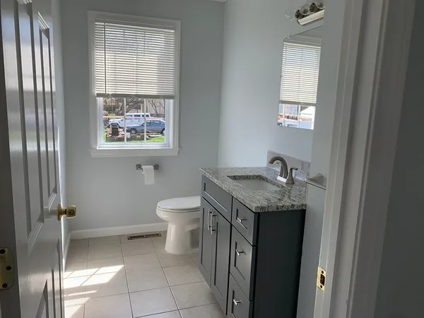 a bathroom with a granite countertop sink a toilet and a window