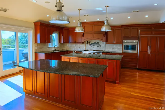 a kitchen with stainless steel appliances granite countertop a stove a sink dishwasher and a microwave with wooden floor