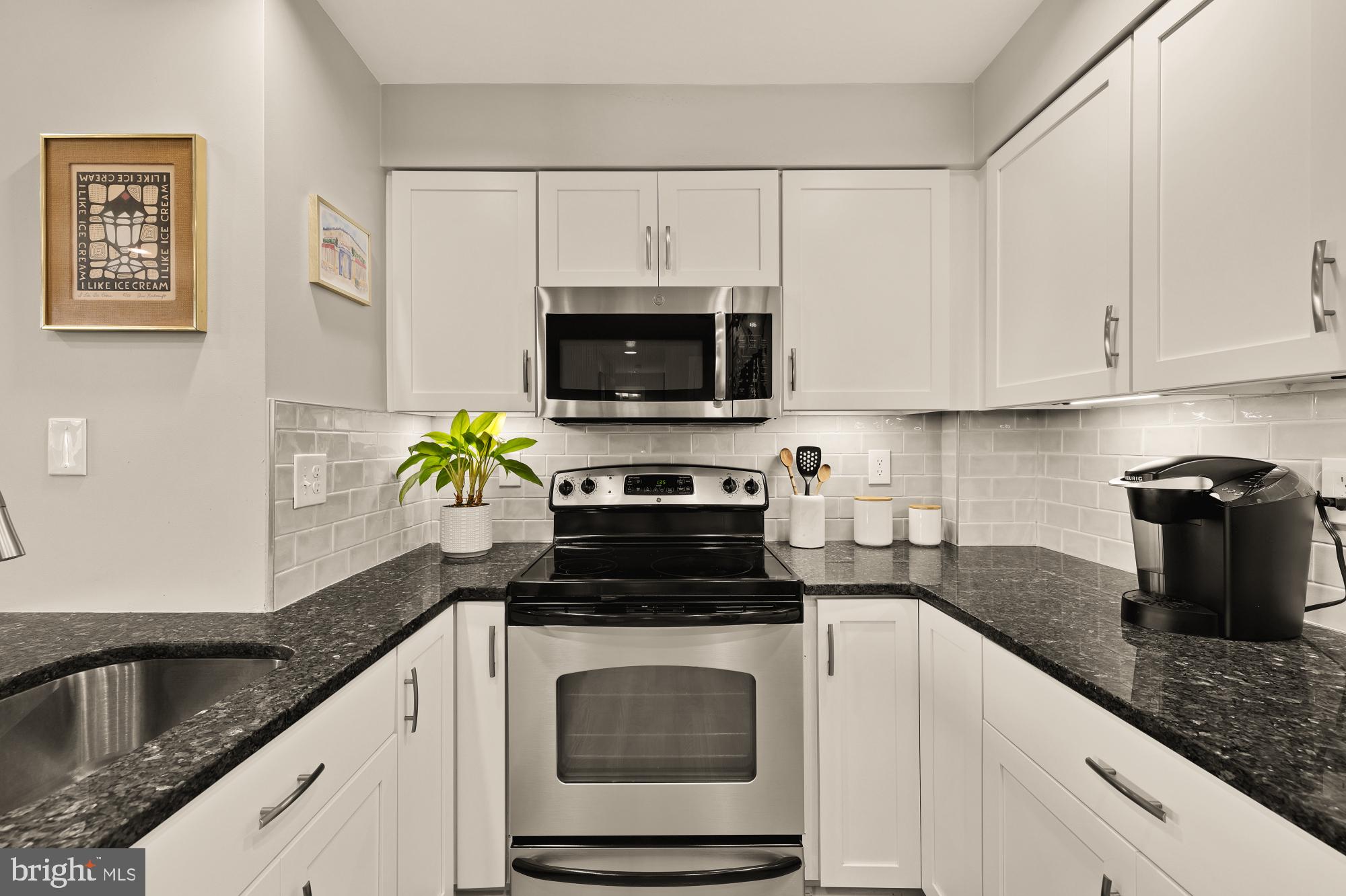 1715 15th Street Northwest, Unit 401 Washington, DC 20009 - Photo 4 of 28 a kitchen with granite countertop white cabinets and black stainless steel appliances