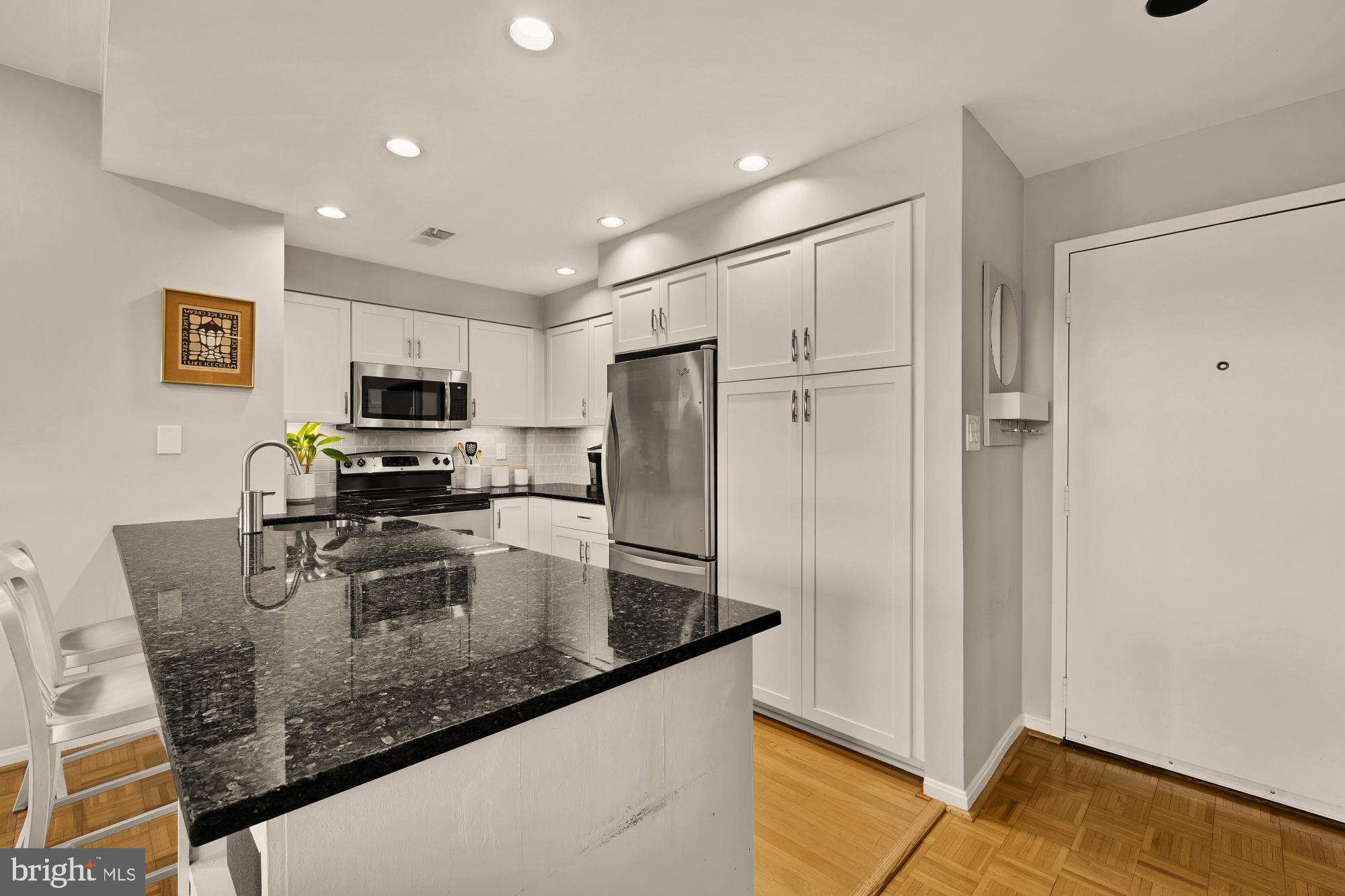 1715 15th Street Northwest, Unit 401 Washington, DC 20009 - Photo 5 of 28 a kitchen with stainless steel appliances granite countertop a refrigerator a stove and a sink with wooden floor