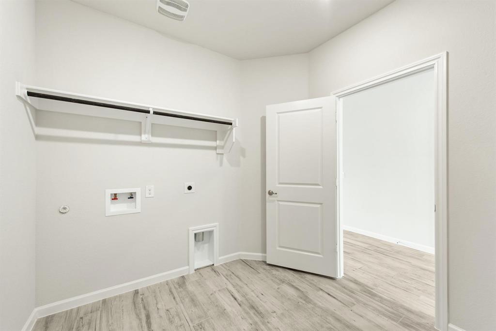 920 Elk Ridge Run Godley, TX 76044 - Photo 21 of 34 Dedicated laundry area featuring a built-in shelving unit with hanging rod, light wood-finish flooring, and crisp white walls