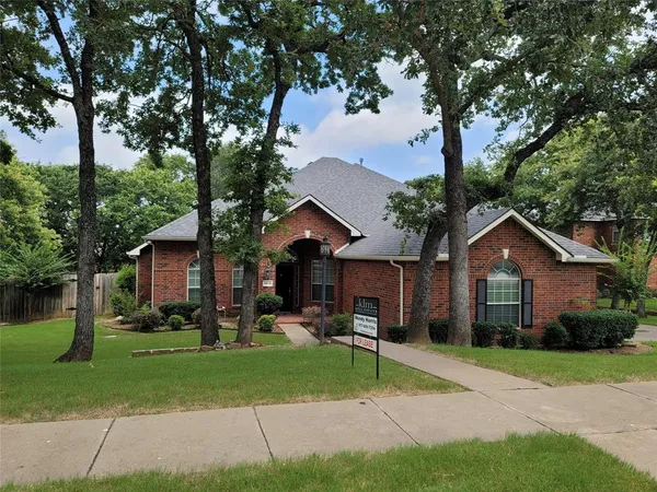 a view of a house with a yard and large tree