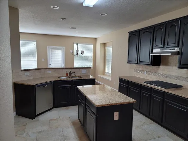 a kitchen with stainless steel appliances granite countertop wooden cabinets a sink and a stove