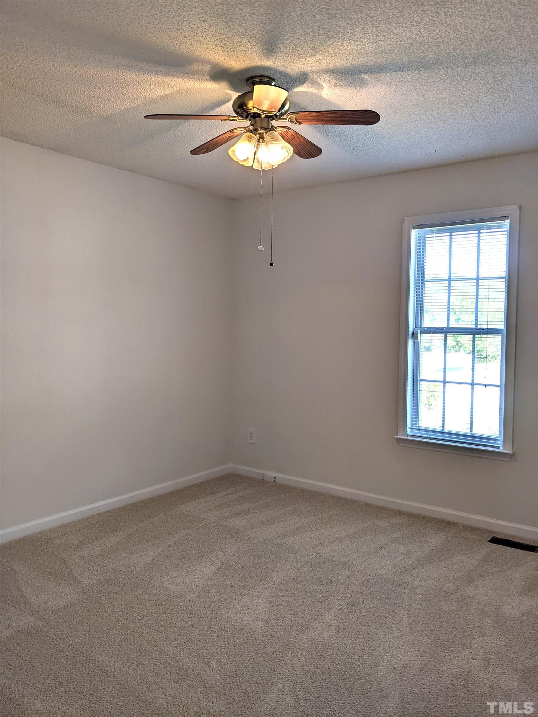 1629 Tall Cane Circle Willow Spring, NC 27592 - Photo 14 of 23 an empty room with a chandelier fan and windows