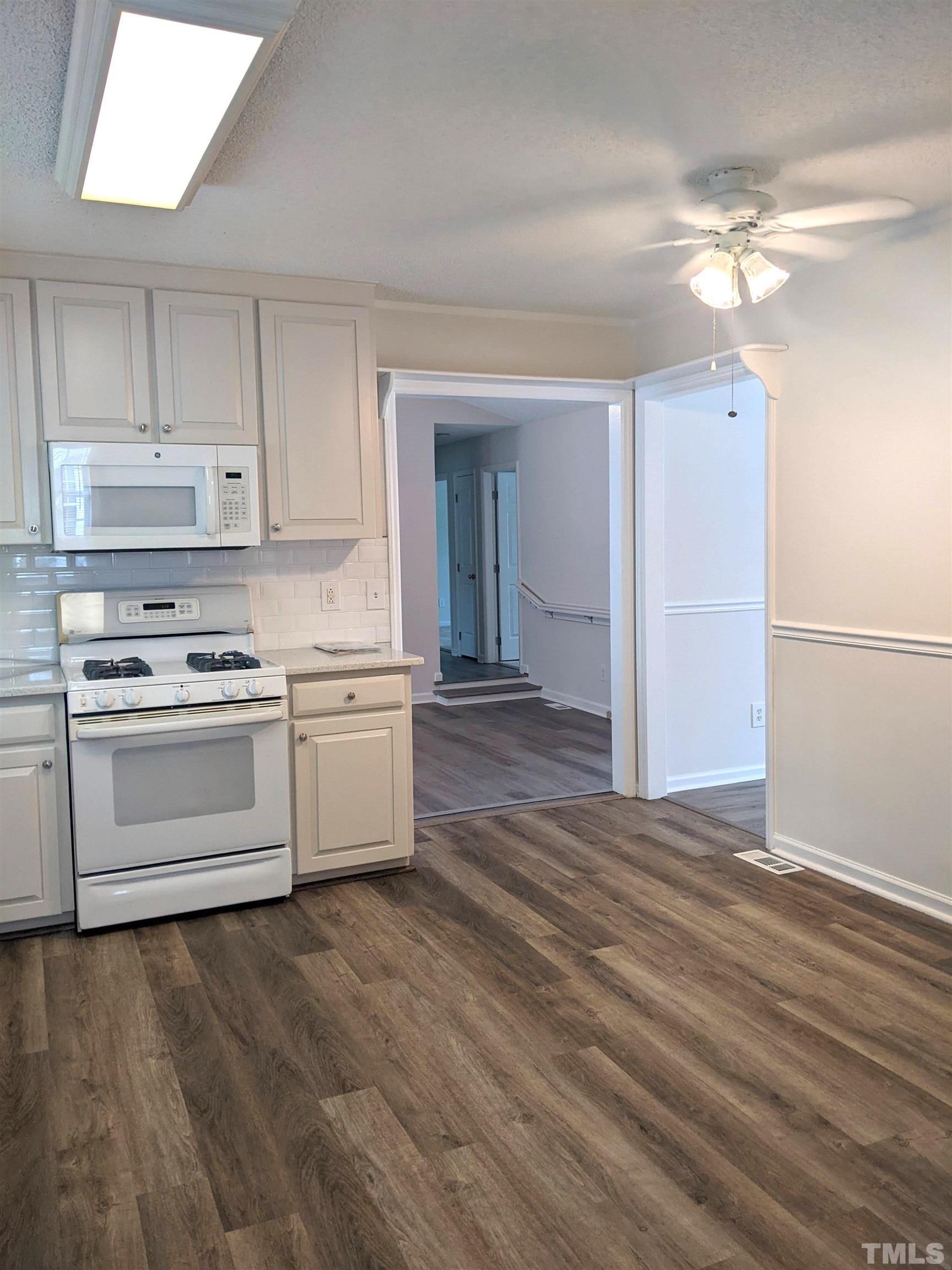 1629 Tall Cane Circle Willow Spring, NC 27592 - Photo 5 of 23 a kitchen with granite countertop white cabinets and white appliances