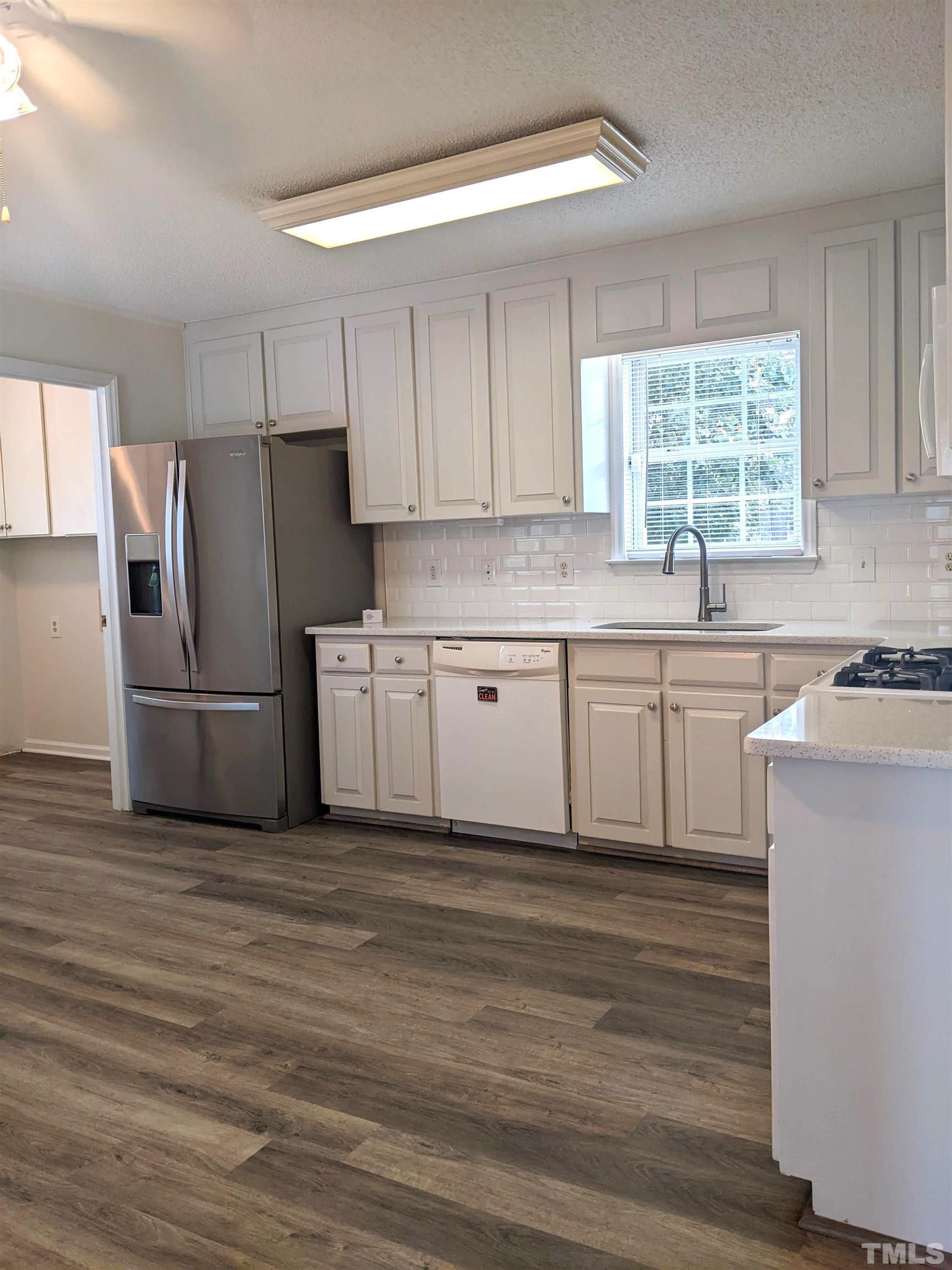 1629 Tall Cane Circle Willow Spring, NC 27592 - Photo 7 of 23 a kitchen with white cabinets stainless steel appliances a sink and a window
