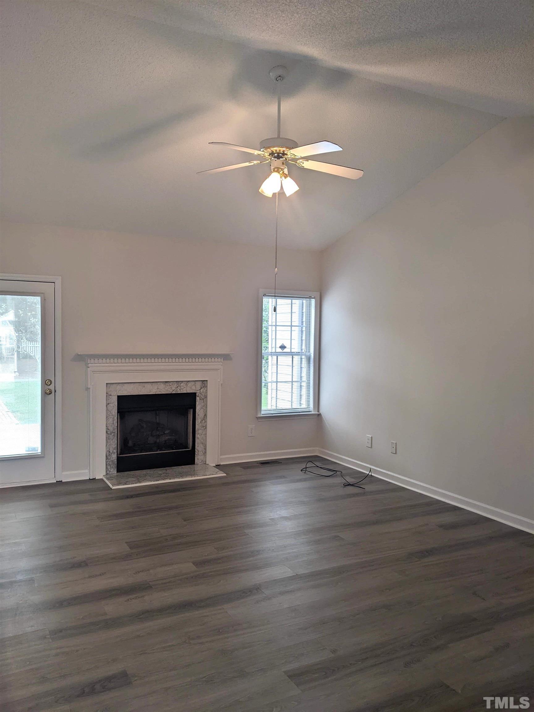 1629 Tall Cane Circle Willow Spring, NC 27592 - Photo 9 of 23 an empty room with wooden floor fireplace and windows