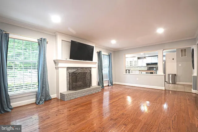 a view of a livingroom with wooden floor and a fireplace