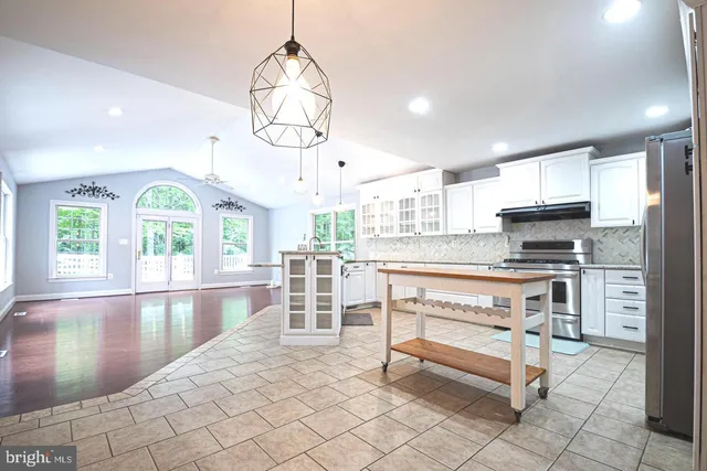 a view of a kitchen with kitchen island a counter top a stove and a wooden floors