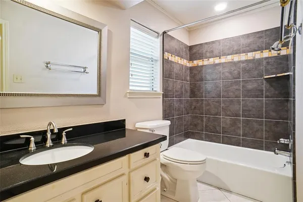 a bathroom with a granite countertop sink a toilet a mirror and bathtub