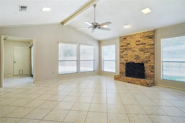an empty room with windows and fireplace