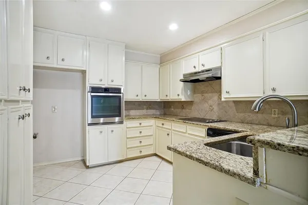 a kitchen with granite countertop white cabinets and stainless steel appliances