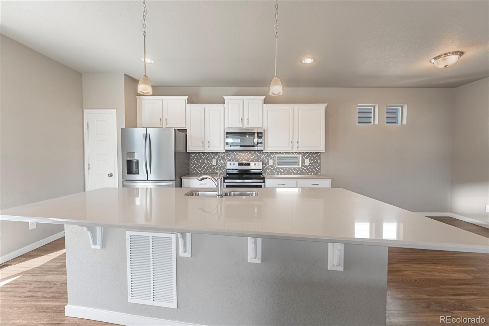 9528 Timberlake Loop Colorado Springs, CO 80927 - Photo 9 of 37 a kitchen with stainless steel appliances granite countertop a refrigerator a stove and a sink with wooden floor