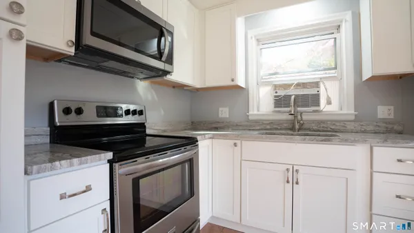 a kitchen with granite countertop stainless steel appliances a stove microwave and sink