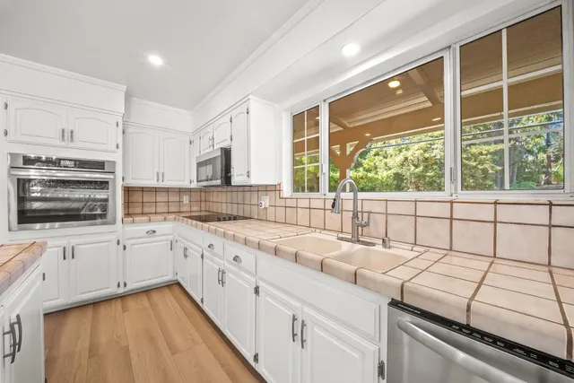 a large white kitchen with kitchen island a stove a refrigerator cabinets and wooden floor