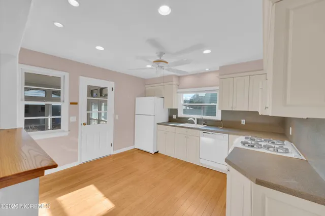 a kitchen with a sink a stove a refrigerator and white cabinets