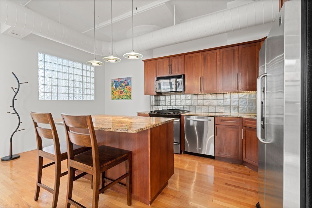 437 D Street, Unit 6A Boston, MA 02210 - Photo 11 of 26 a kitchen with stainless steel appliances granite countertop a stove top oven a sink dishwasher and a refrigerator