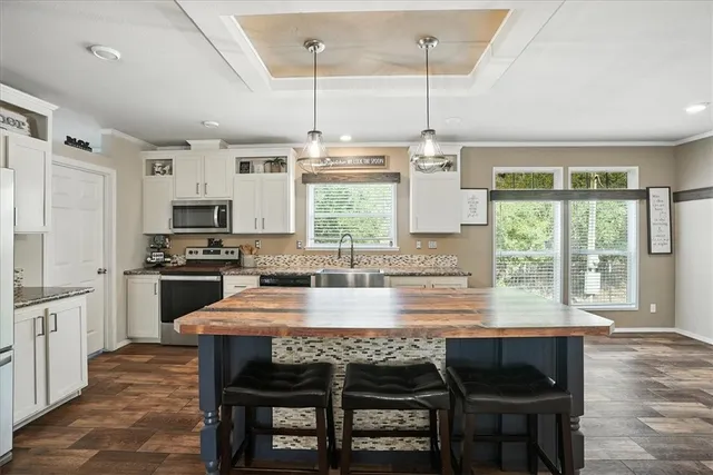 a kitchen with kitchen island granite countertop a stove a sink a oven a dining table and chairs