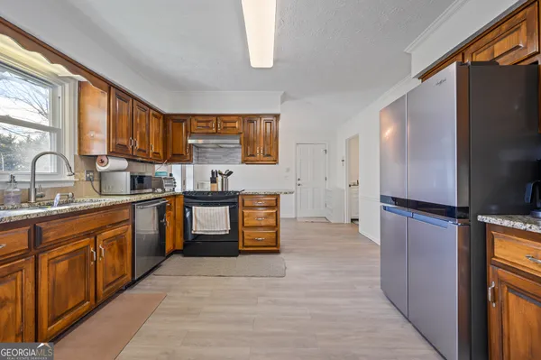 a kitchen with granite countertop a refrigerator stove top oven and sink