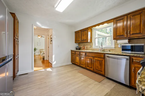 a kitchen with stainless steel appliances granite countertop a refrigerator a sink dishwasher a stove with wooden cabinets and floor