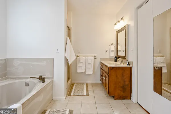 a spacious bathroom with a tub sink and mirror