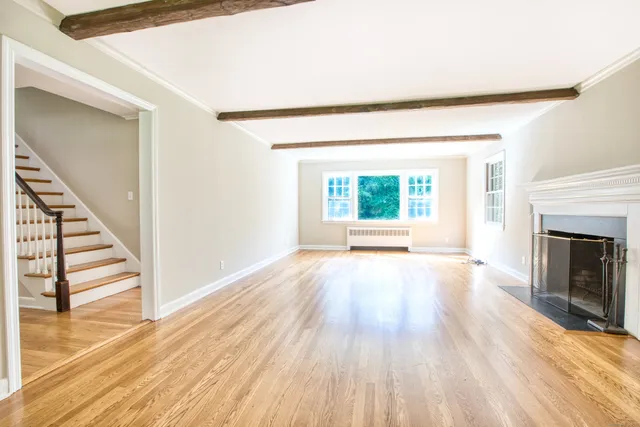 a view of an empty room with wooden floor fireplace and a window