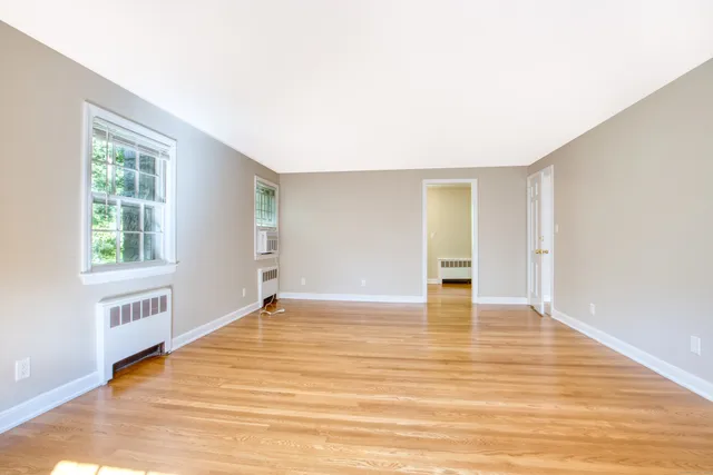 a view of an empty room with wooden floor and a window