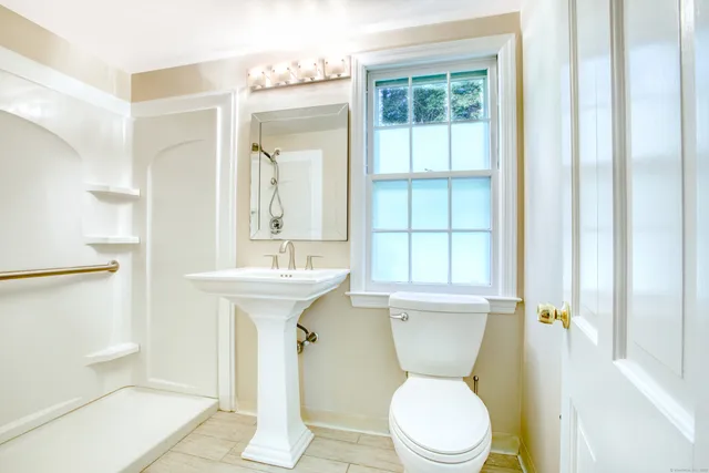 a bathroom with a toilet a sink and a window