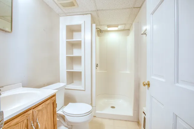 a bathroom with a granite countertop toilet a sink and shower