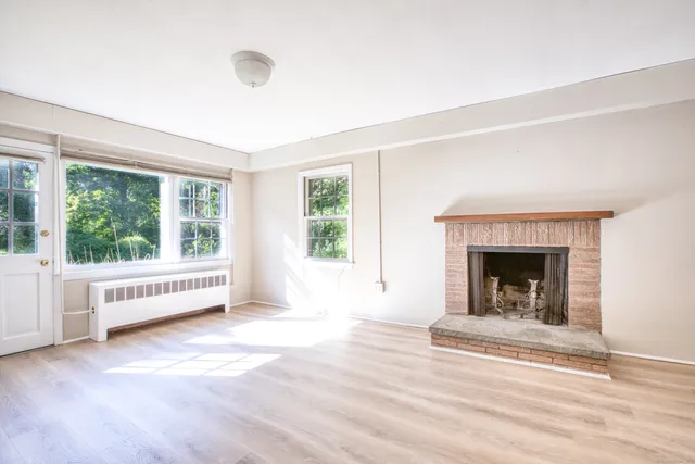 a view of an empty room with a fireplace and a window
