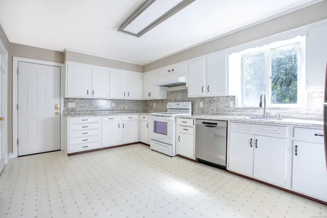 a kitchen with white cabinets sink and window
