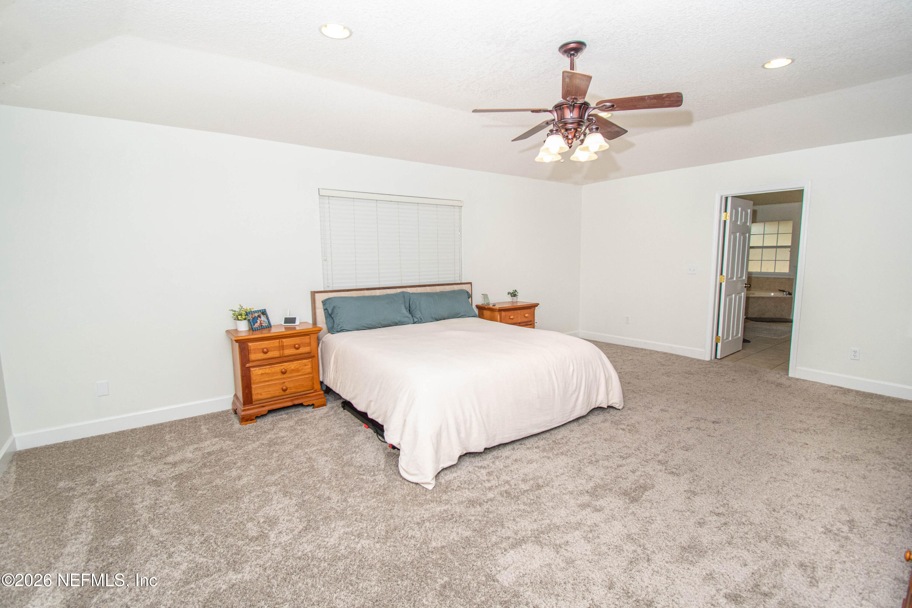 7733 Odis Yarborough Road Glen St. Mary, FL 32040 - Photo 22 of 45 a spacious bedroom with a bed and a chandelier