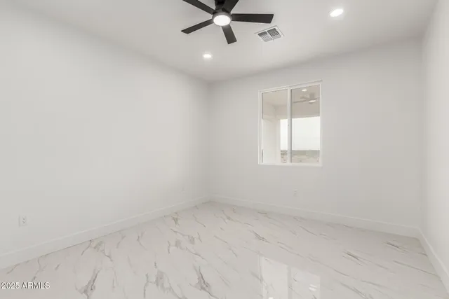 an empty room with a window and a fan