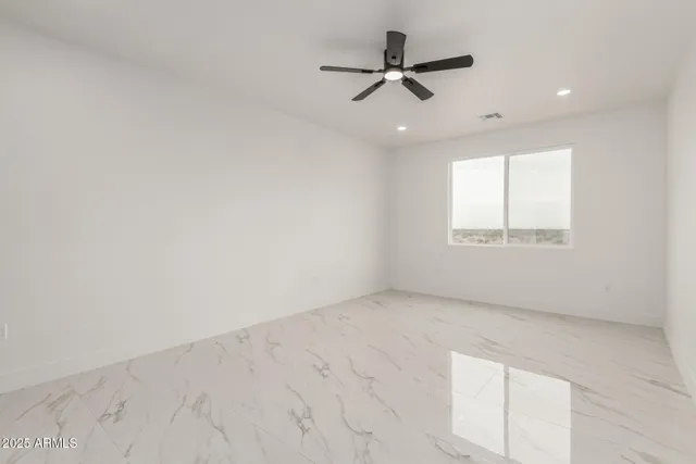 an empty room with a window and a ceiling fan