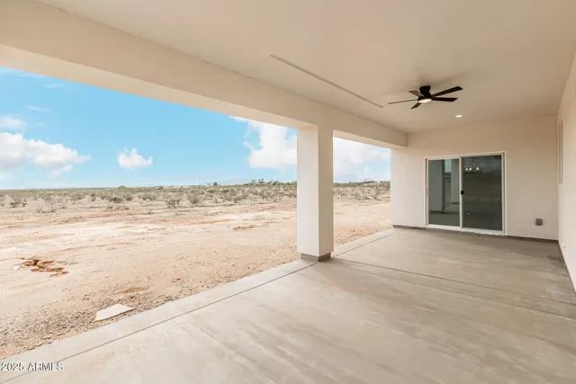 a view of an empty room with window and chandelier fan