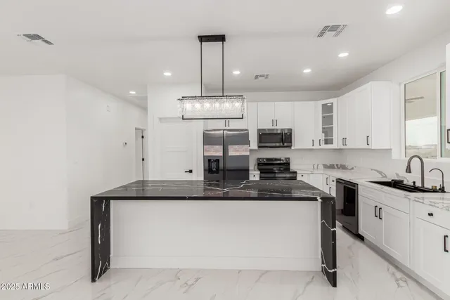 a kitchen with kitchen island granite countertop a sink cabinets and stainless steel appliances