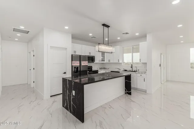 a kitchen with stainless steel appliances kitchen island granite countertop a refrigerator and a sink
