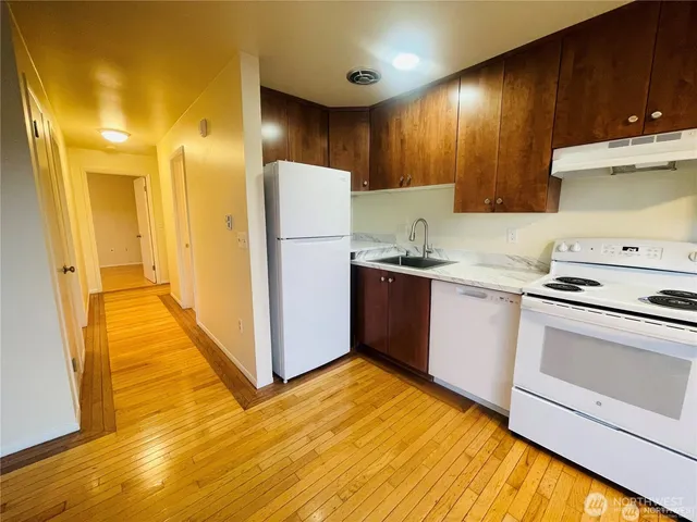 a kitchen with a sink a stove cabinets and wooden floor