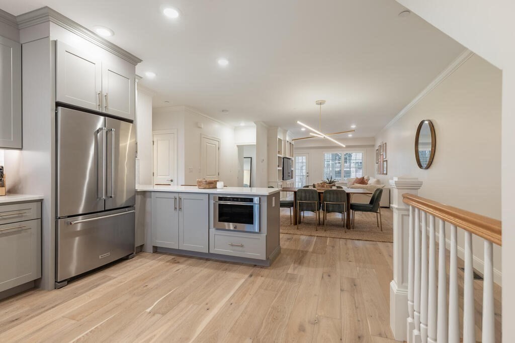 165 Cambridge Road, Unit 10 Woburn, MA 01801 - Photo 6 of 33 a kitchen with granite countertop a refrigerator a sink dishwasher a stove and white cabinets with wooden floor