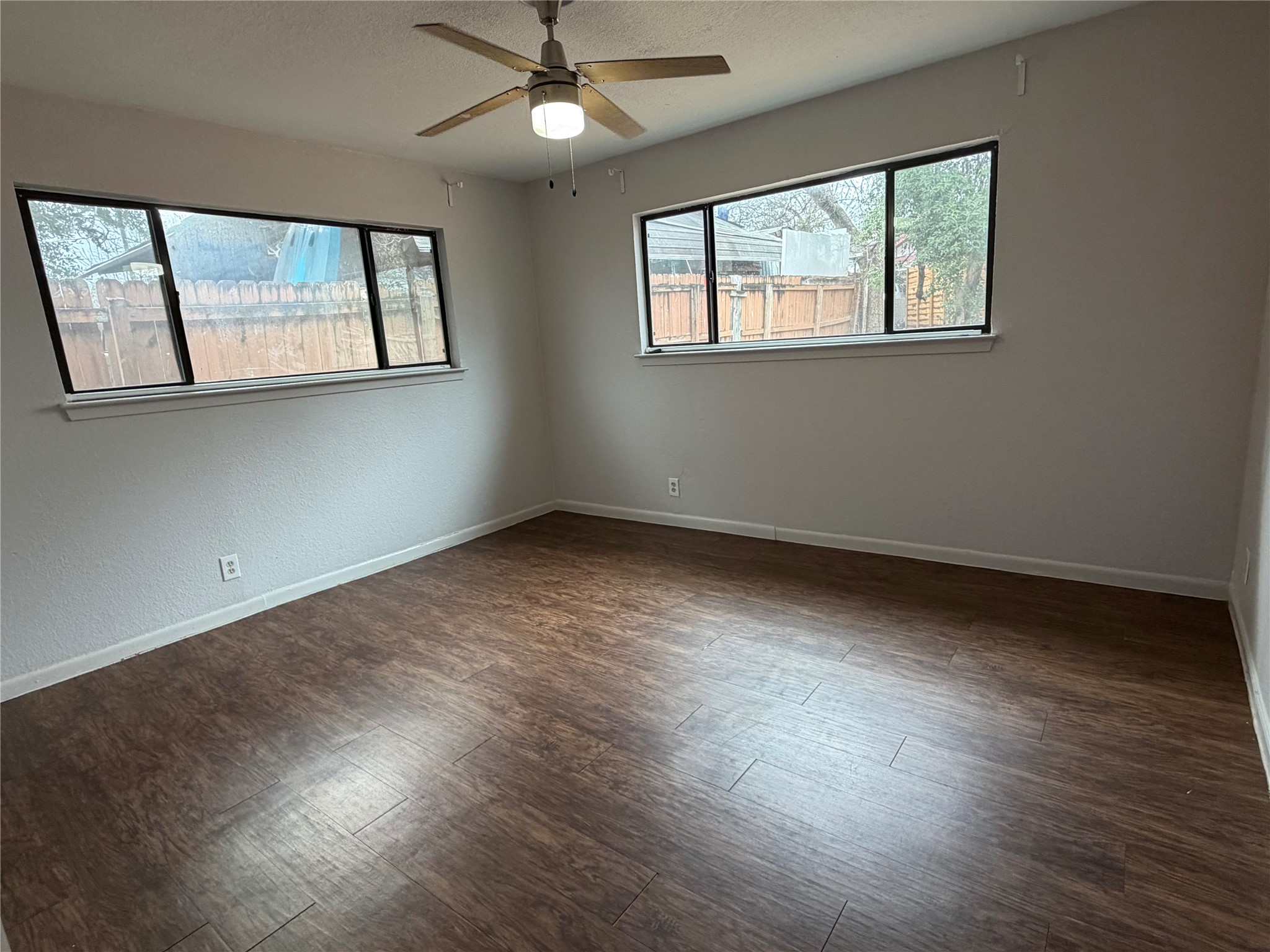 7404 Bethune Avenue, Unit B Austin, TX 78752 - Photo 11 of 13 Unfurnished room with plenty of natural light, a ceiling fan, a textured ceiling, dark wood-style floors, and a textured wall